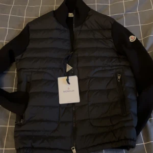Svart cardigan jacka från Moncler - Snygg svart cardigan jacka från Moncler med dragkedja och långärmade ärmar. Perfekt för vintern men också våren. Lappen är kvar fick i julklapp men den va för liten. Har tyvärr inget kvitto men fråga gärna om du undrar nått!
