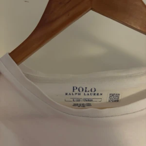 Vit ralph lauren  t-shirt  - Säljer en klassisk vit t-shirt från Ralph Lauren med den ikoniska broderade loggan på bröstet. Perfekt för en stilren och avslappnad look. T-shirten är kortärmad och tillverkad i mjuk bomull. Äkta 100%. Säljs för 230