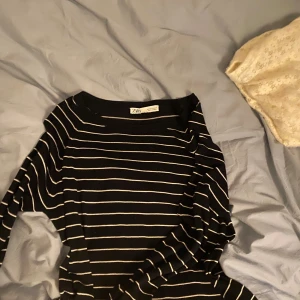 Svart och vit randig tröja från Zara - Säljer en stilren svart tröja med vita ränder från Zara. Tröjan har en klassisk design med rund hals och långa ärmar. Perfekt för en avslappnad men ändå chic look.