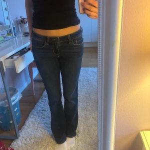 Mörkblå jeans med bootcut - Snygga mörkblå jeans med bootcut-stil och låg midja. Klassisk design med fem fickor och knappgylf.