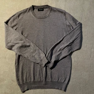 Grå tröja från Sand Copenhagen - Snygg grå/beige tröja från Sand Copenhagen med rund halsringning. Perfekt för en stilren look. Tröjan har långa ärmar och är tillverkad i ett mjukt material.