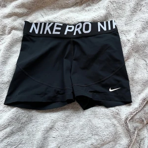 Svarta träningsshorts från Nike - Snygga svarta träningsshorts från Nike med elastisk midja och vit logga. Perfekta för intensiva träningspass eller löpning. Bekväma och stilrena med en tight passform💅🏼🤍