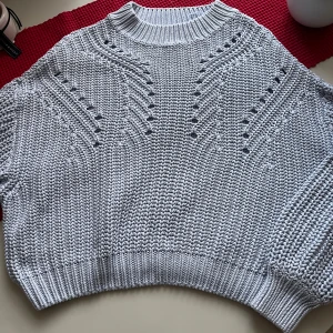 Grå stickad tröja med mönster - Säljer en snygg grå stickad tröja med ett unikt mönster. Tröjan har en ribbad krage och långa ärmar, perfekt för kyligare dagar. Den är både stilren och bekväm, ett måste i garderoben!