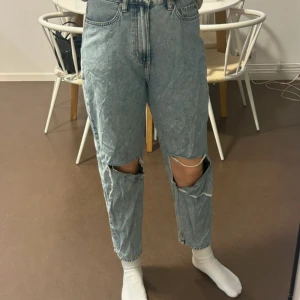 Blå ripped jeans - Snygga blå jeans med hög midja och slitningar på knäna. De har en straight passform och klassisk femficksdesign. Perfekta för en avslappnad stil.