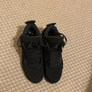 Svarta Nike Air Jordans - Säljer ett par helsvarta Nike Air Jordans med snygg design och ikonisk logga. Skorna har snörning och en robust sula för extra komfort. Perfekta för dig som vill ha en stilren look.