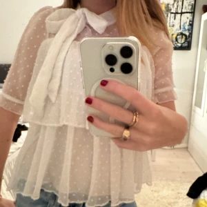 Vit blus med prickar och rosett - sån gullig coh somrig topp med massa detaljer. Kommer tyvärr ej till användning lägnre därav säljs den. Den har en liten sminkfläck vid kragen men går bort i tvätten🥰🥰