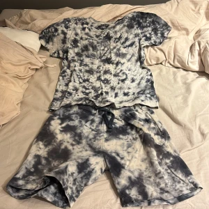 Svartvit batikmönstrad t-shirt och shorts - Säljer en cool svartvit batikmönstrad t-shirt med matchande shorts. T-shirten är kortärmad och setet är perfekt för en avslappnad stil. Materialet ser mjukt och bekvämt ut, idealiskt för varma dagar. Är samma storlek på T-shirten och shortsen.