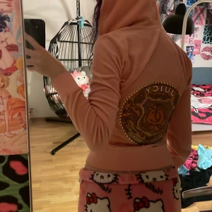 Rosa hoodie från Juicy Couture - Säljer en snygg rosa hoodie från Juicy Couture med dragkedja och en stor glittrig logga på ryggen. Tröjan har långa ärmar och är gjord i ett mjukt material.💓