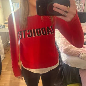 Röd tröja från Zadig & Voltaire - Snygg röd tröja från Zadig & Voltaire med texten 'ZADDICTED' på bröstet. Tröjan har en rund halsringning och är perfekt för en casual look. Den är tillverkad i ett mjukt material som känns skönt mot huden.