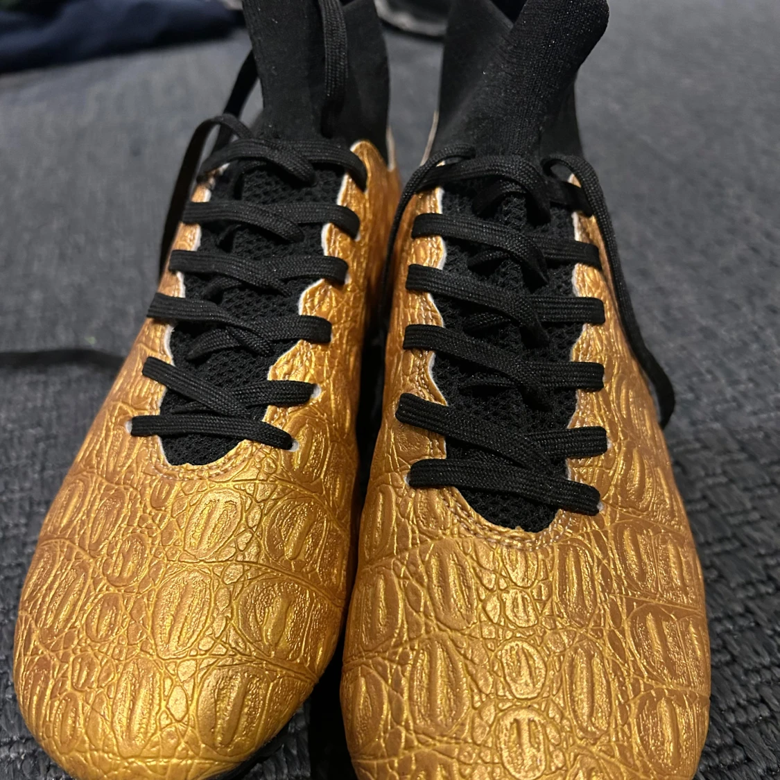 Guldiga fotbollsskor med svart snörning