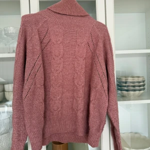 Rosa stickad polotröja - Mysig rosa stickad polotröja med kabelstickat mönster och långa ärmar. Bra skick.   