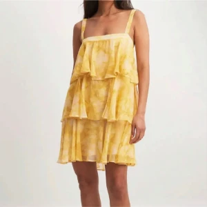 Gul klänning med volanger - Säljer en söt gul klänning med volanger och knytning i ryggen. Köpt här på plick men inte kommit till användning, har lagat bandet som va trasigt, strl 42 men som en 40  