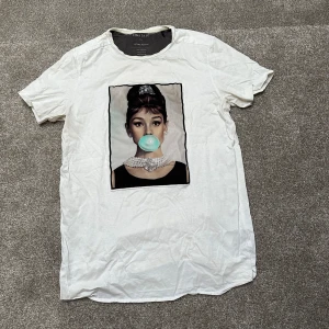 Vit t-shirt med tryck från Limitato - Snygg vit t-shirt från Limitato med ett coolt tryck av en kvinna som blåser en bubbla. Perfekt för en avslappnad stil med en twist. Tillverkad i Portugal. Storlek L.