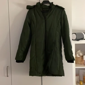 Grön quiltad parkajacka - Snygg grön parkajacka med quiltad design och dragkedja. Jackan har en huva och långa ärmar, perfekt för kyligare dagar. Den är stilren och funktionell, vilket gör den till ett bra val för höst och vinter men också nu inför våren!!🫶
