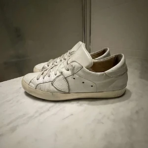 Vita sneakers från Golden Goose - Snygga vita sneakers från Golden Goose med klassisk design och snörning. Skorna har en diskret stjärndetalj på sidan och en bekväm sula. Perfekta för en stilren look.