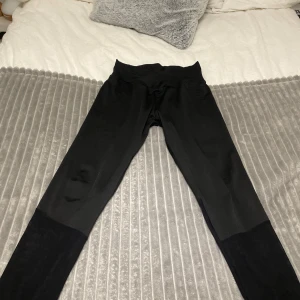Svarta leggings med meshdetaljer - Snygga svarta idrottsbyxor med transparenta meshdetaljer vid benen, med en fin detalj vid midjan.