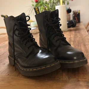 Svarta boots från Dr. Martens - Klassiska svarta Dr. Martens boots med snörning och den ikoniska gula sömmen runt.