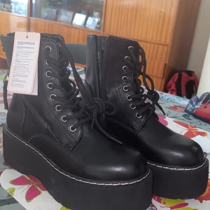 Svarta kängor med äkta skinn av märket DeeZee - Snygga svarta platåkängor i äkta skinn med snörning och dragkedja på sidan. De har en rejäl platåsula som ger extra höjd och stil. Perfekta för att ge din outfit en edgy touch. Lätt att få på och av. Perfekta vårskor utan foder. 