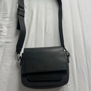 Svart handväska - Jättefin, svart axelremsväska från Carin Wester. I väldigt bra skick, men lite ”smårostig” vid magneten som stänger väskan, men det är inget som syns. Bandet går att justera och väskan är i perfekt, lite mindre storlek. Kan skicka mått vid intresse🥰