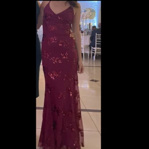 Vinröd paljettklänning / balklänning  - Elegant vinröd långklänning med glittriga paljetter och smala axelband. Snörning i ryggen. Jag är 159 cm använd endast en gång på ett bröllop. Ej öppet köp! Passar klänningen inte dig så får du själv sälja den! Klänningen är granskad och den är så gott som ny! Ej hål osv. Postar oftast samma dag! 