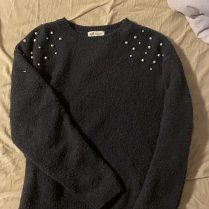 Marinblå tröja med pärlor från H&M - Säljer en tröja från H&M, tröjan är marinblå och har vita pärlor på axlarna. Den passar mig bra som vanligtvis är en xs/s, bra skick !🩷
