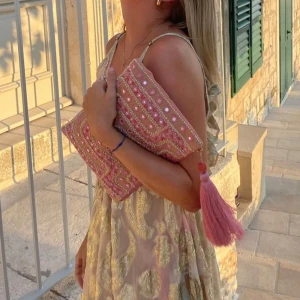 Ibiza style clutch - SLUTSÅLD Snygg rosa kuvertväska med detaljerat broderi och en stor tofs. Väskan har ett unikt mönster med pärlor och paljetter som ger en festlig känsla. Perfekt för att lyfta din outfit med lite extra färg och stil. Ibiza style clutch, från Indiska nypris 350kr, Nyskick, väska, necessär, paljetter, glitter, rosa, sequins, sommar.