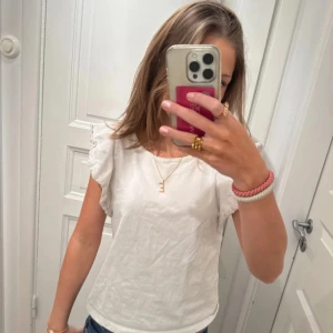 Vit topp med volangärmar - Säljer en söt vit topp med volangärmar. Perfekt för en somrig look. Toppen är gjord i mjukt bomullsmaterial och har en rund halsringning. Passar bra till både jeans och kjol. 🌸