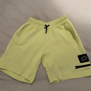 Ljusgröna shorts från Zara - Snygga ljusgröna shorts från Zara med snörning i midjan och en cool svart detalj på benet. Perfekta för en avslappnad stil. De har praktiska fickor och en bekväm passform.