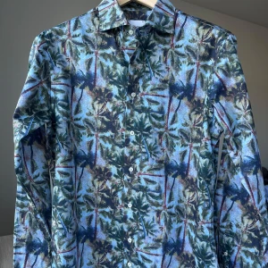 Mönstrad skjorta från Oscar of Sweden - Oscar Jacobson. Slim fit, storlek 40. 100% bomull, fin och mjuk. Nyskick. Jag säljer många skjortor i samma storlek, kolla gärna på mina övriga annonser för att skapa ett paket. Axelbredd: 47 cm Längd: 74 cm  Casual skjorta, smart, hawaii, sommar, mönster, palmer, oscar of sweden.