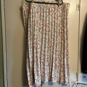 Blommig kjol från Isolde - Säljer en vacker blommig kjol från Isolde i rosa och vit. Kjolen har ett elastiskt midjeband och ett luftigt fall, perfekt för varma dagar. Den har ett fint blommönster som ger en romantisk känsla. Köpte från second hand med syfte att göra något med tyget men har bara skjutit fram det såpass länge, så nu tänker jag att någon annan kanske kan få lycka av den :) 