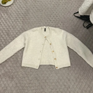 Vit kofta från H&M Divided - Säljer en mysig vit kofta från H&M Divided. Koftan har långa ärmar och knappar framtill. Perfekt för kyliga dagar och enkel att matcha med olika outfits.