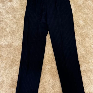 Svarta randiga kostymbyxor från Bläck - Svart kavaj med en knappslå och två fickor fram. Kavajen har en klassisk passform och är perfekt för både vardag och fest.  Strl: 48 Skick: mycket bra skick Ord. Pris: 499 Säljes då den blivit liten på mig  Din stil: spara inlägget så du inte missar denna kappa Inte din stil: Kolla min profil. Du kommer hitta något för alla kön och åldrar.