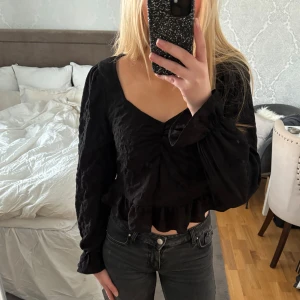 Svart blus med volangdetaljer - Snygg svart blus med volangdetaljer och långa ärmar