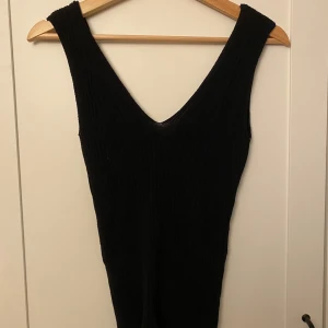 Svart ribbat linne från Vila - Snygg svart ribbat linne från Vila i storlek XS. Linnet har en stilren design med en djup v-ringning och är ärmlös. 