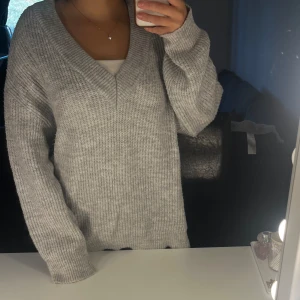 Grå stickad tröja med v-ringning - Mysig och stilren grå stickad tröja med v-ringning. Köpt från Gina tricot i storlek M. Perfekt för kyliga dagar och passar till både vardag och lite finare tillfällen. 