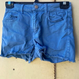 Blå shorts från H&M - Säljer ett par snygga blå shorts från H&M. De är i storlek 152 och har en cool fransig kant nertill. Perfekta för sommardagar! 🩵