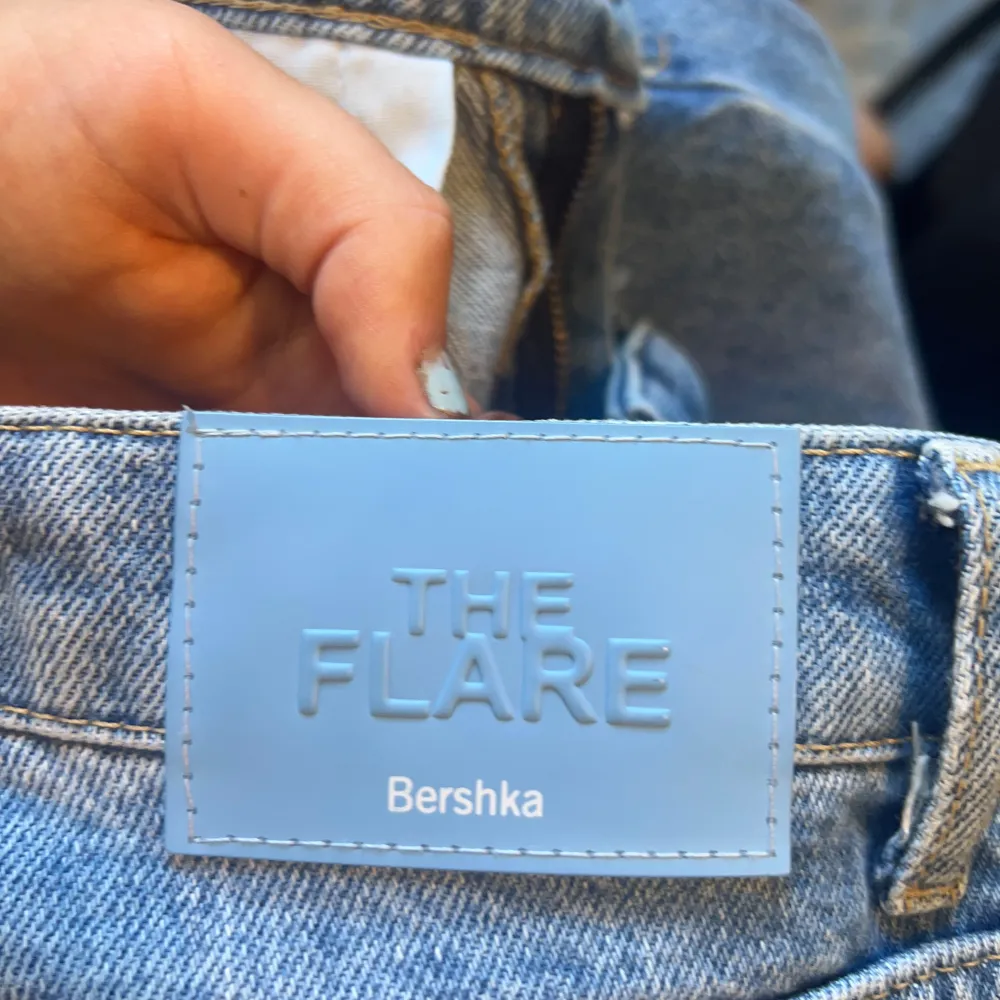 Säljer ett par snygga blå jeans från Bershka i modellen 'The Flare'. De har en cool slitning vid knäna och är i en skön denimkvalitet. Perfekta för en avslappnad stil med en touch av edge. Passar bra till både vardag och fest!. Jeans & Byxor.