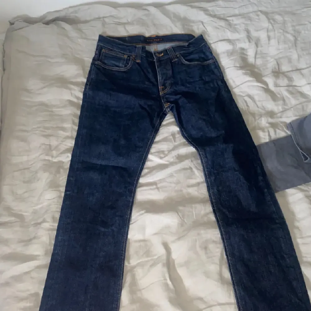 Snygga mörkblåa nudie jeans i väldigt bra skick, inga defekter förekommer. Säljs eftersom jag bytt stil. Sitter straight/slim. Jeans & Byxor.