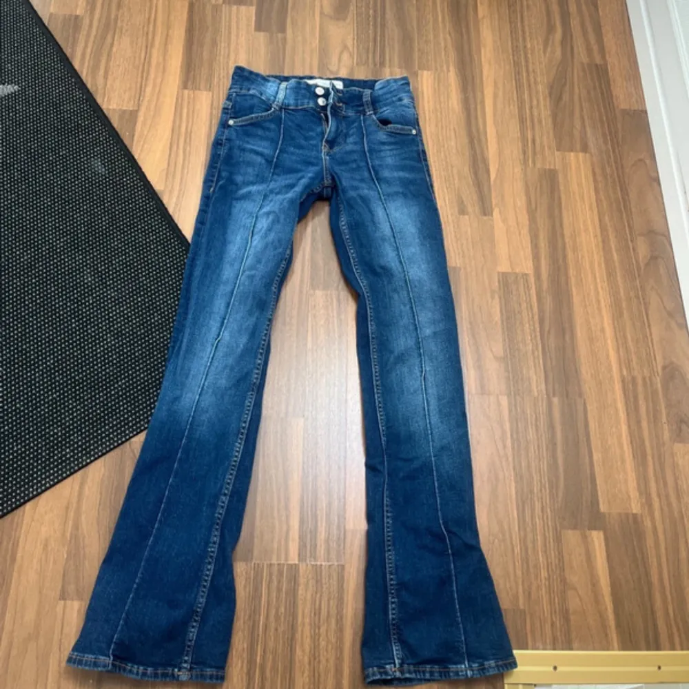 Säljer ett par snygga low waist blå bootcut jeans från Bershka. De har en klassisk femficksdesign och stängs med två knappar och dragkedja. Jeansen är i bra skick och perfekta för både vardag och fest. Finns ej kvar på Bershka.. Jeans & Byxor.