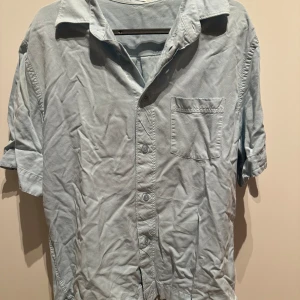 Ljusblå kortärmad skjorta - Filippa K - Storlek 46 - Ljusblå kortärmad skjorta från Filippa K med bra stadga och kvalité. Inga defekter alls och har storlek 46. Normal passform.