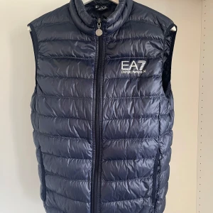 EA7 Väst - Säljer min mrinblåa EA7 Väst i riktigt bra skick. Inte använd mycket. Västen är i storlek L men sitter som om det vore en storlek M. (Har M i alla mina andra kläderk). Är 185cm och väger 66kg. 