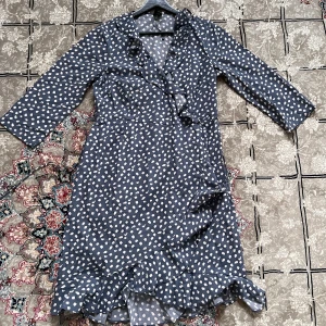 Mörkblå prickig klänning med volang - Säljer en superfin mörkblå klänning med vita prickar. Den har trekvartsärmar och en söt volangdetalj längst ner. Perfekt för både vardag och fest! 💙