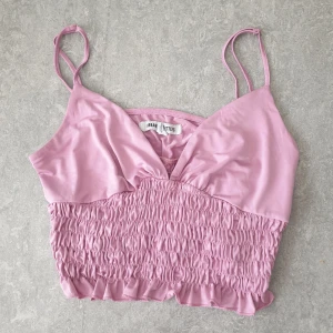 Urban Outfitters topp - Jätte fin smockad topp från Urban Outfitters  Storlek L, stretchig. Väldigt bra skick. Sitter jättefint på men tyvärr för liten för mig.   Smockad crop top med plunge neckline