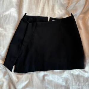 Minikjol  - Svart minikjol med låg midja från WEEKDAY. Asymmetrisk form. Passar XS