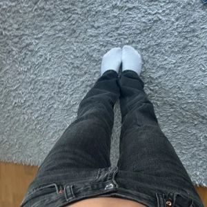 Svarta jeans med rak passform - Säljer ett par svarta jeans med rak passform. De är i bra skick och har en klassisk design med fem fickor och knappgylf. Perfekta för vardagsbruk!