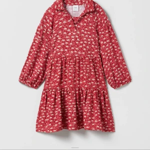 Röd blommig klänning från Zara - Säljer en superfin röd klänning från Zara med ett gulligt blommönster. Klänningen har långa ärmar och en bekväm passform, perfekt för både vardag och fest. Den är gjord i ett mjukt material som känns skönt mot huden.