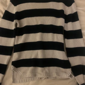 Randig stickad tröja - Stickad tröja från 2000, knappt använd av mig men är använd innan. Slits nere i kanterna och ryggen är några cm längre, lite sliten därav priset