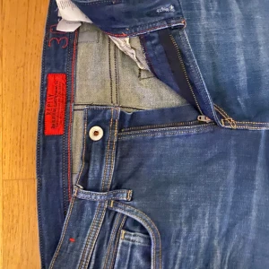 Blå jeans från Replay - Snygga blå jeans från Replay med klassisk femficksdesign och dragkedja. De har en normal passform och är perfekta för en avslappnad stil. Detaljer som kontrastsömmar och märkets logga på bakfickan ger en extra touch.