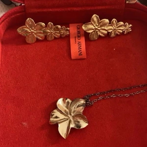 Guldblommigt smyckeset - Elegant smyckeset Setet innehåller ett halsband och ett par örhängen, båda med vackra blomdetaljer. Perfekt för att lägga till en touch av lyx till din outfit. Går o diskutera pris