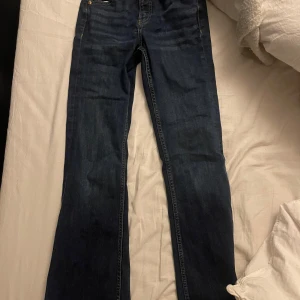Mörkblå jeans från Kappahl - Snygga mörkblå jeans från Kappahl med klassisk design. De har en rak passform och är perfekta för en avslappnad stil. Jeansen har fem fickor och knappar i metall.